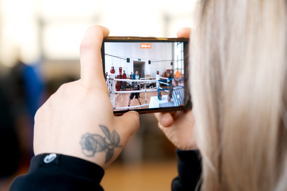 Divák natáčí boxerský zápas v ringu mobilním telefonem.