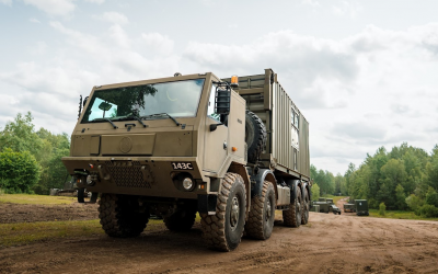 Tatra 815-7 8×8 v provedení hákového nakladače při přepravě kontejneru v terénu.