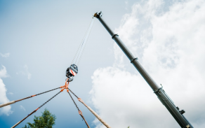 Obsluha jeřábu při práci s teleskopickým výložníkem během přesunu těžkého břemene.