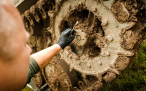 Voják manipuluje s pojezdovým kolem pásového vozidla při opravě v terénu