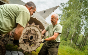 Spolupráce vojáků při demontáži poškozené části podvozku pásové techniky.