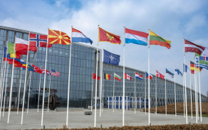 Sídlo NATO v Bruselu s vlajkami členských států. Kolektivní obrana Aliance stojí na jednotě, připravenosti a společném postupu spojenců.