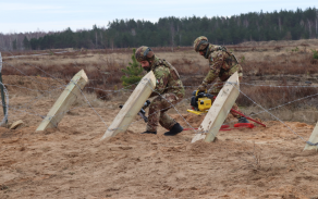 Italští ženisté překonávají český nevýbušný zátaras za pomoci pneumatických kleští.